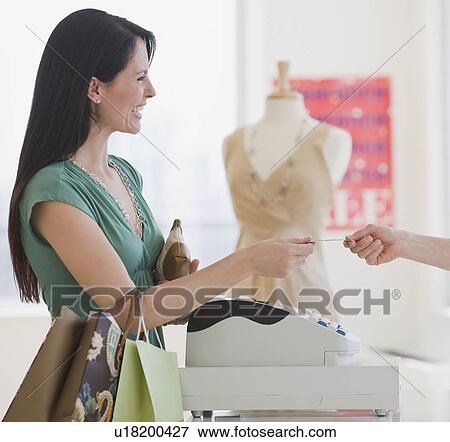 Stock Photo - Woman paying for purchase at boutique. Fotosearch
