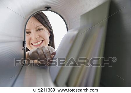 Stock Photo - Woman reaching into mailbox for mail. Fotosearch