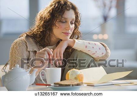 Woman reading letter and stirring tea View Large Photo Image Stock Photo - Woman reading letter and stirring tea. Fotosearch