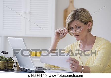 Stock Photo - Woman reading mail next to laptop. Fotosearch