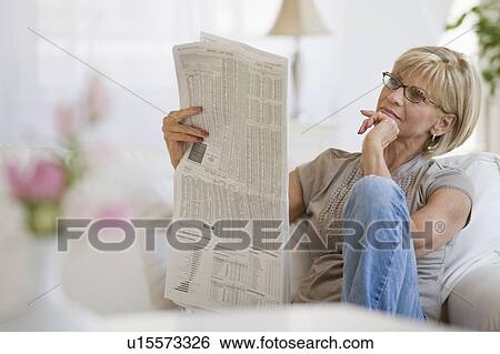 Woman reading newspaper in livingroom View Large Photo Image Stock Photograph - Woman reading newspaper in livingroom. Fotosearch