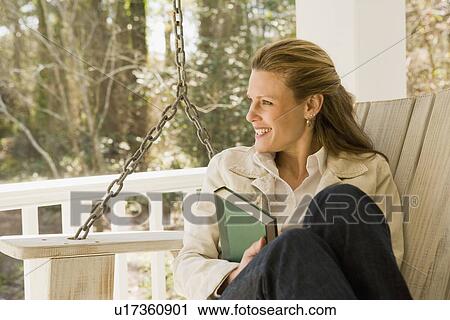 Woman relaxing with book on porch swing View Large Photo Image Stock Image - Woman relaxing with book on porch swing. Fotosearch