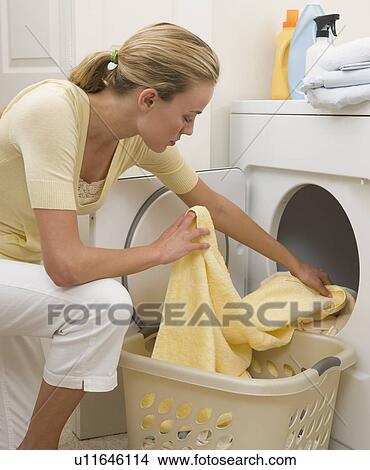 Picture - Woman removing towels from dryer. Fotosearch