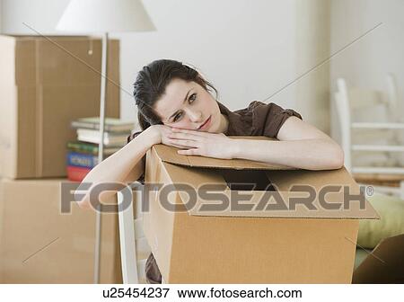 Stock Photo - Woman resting on moving box. Fotosearch