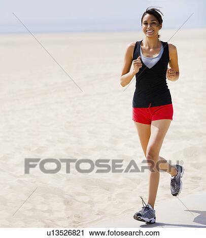 Stock Image - Woman running on beach. Fotosearch