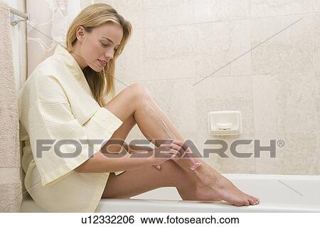 Stock Photograph - Woman shaving legs on edge of bathtub. Fotosearch