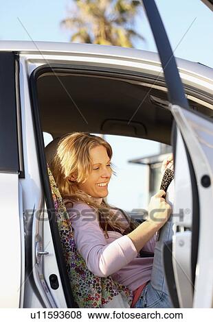 Stock Photo - Woman sitting in car with door open. Fotosearch