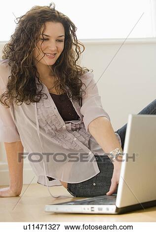 Stock Photo - Woman sitting on floor using laptop. Fotosearch