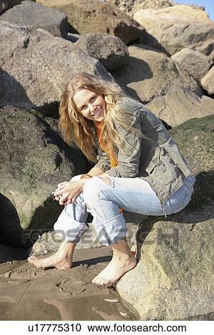 Stock Image - Woman sitting on rock. Fotosearch