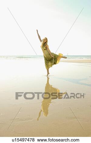 Stock Photo - Woman standing on one foot at beach. Fotosearch