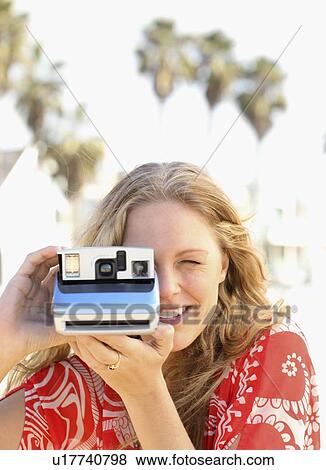 Woman taking photograph with instant camera View Large Photo Image Stock Photo - Woman taking photograph with instant camera. Fotosearch