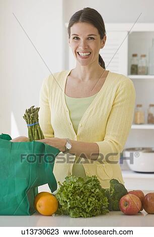 Stock Image - Woman unpacking groceries. Fotosearch