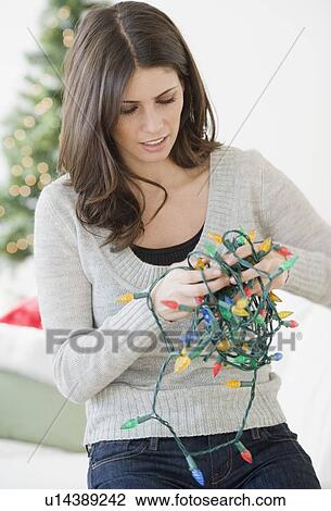 Woman untangling Christmas lights View Large Photo Image Stock Image - Woman untangling Christmas lights. Fotosearch