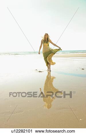 Stock Image - Woman walking on beach. Fotosearch