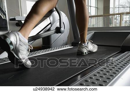 Stock Image - Woman walking on treadmill. Fotosearch