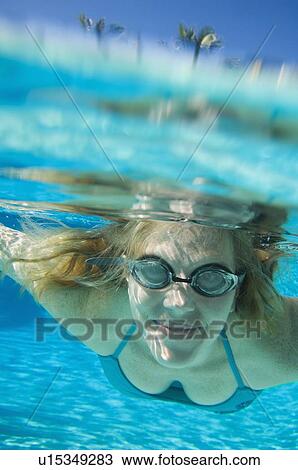 Stock Image - Woman wearing goggles underwater. Fotosearch