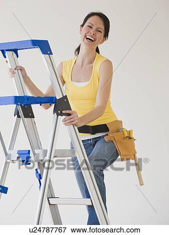 Woman wearing tool belt climbing ladder View Large Photo Image Stock Photo - Woman wearing tool belt climbing ladder. Fotosearch