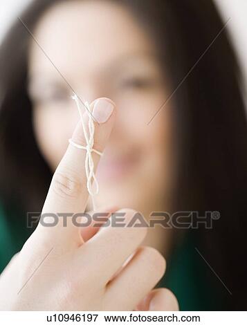 Woman with string tied around finger View Large Photo Image Stock Photo - Woman with string tied around finger. Fotosearch
