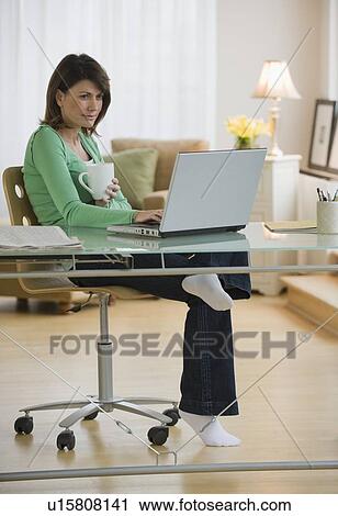 Stock Image - Woman working on laptop in home office. Fotosearch