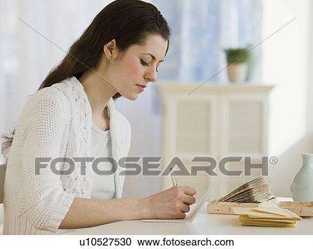Stock Image - Woman writing at table. Fotosearch