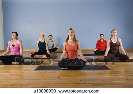 Stock Image - Women exercising in yoga class. Fotosearch