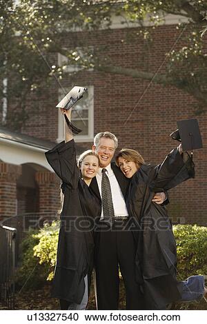 Stock Image - Women graduates with father cheering. Fotosearch