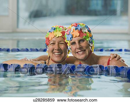 Stock Photo - Women in swim caps hugging in swimming pool. Fotosearch