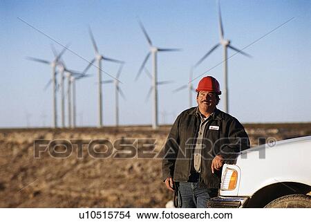 Worker leaning against truck with wind turbines in background View Large Photo Image Picture - Worker leaning against truck with wind turbines in background. Fotosearch