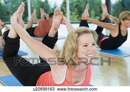 Stock Image - Yoga class in bow pose. Fotosearch