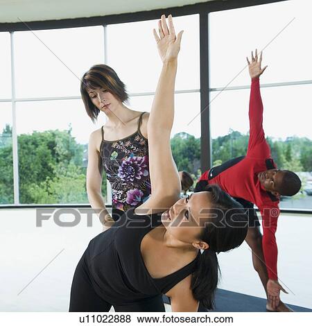 Yoga instructor helping woman with triangle pose View Large Photo Image Stock Photo - Yoga instructor helping woman with triangle pose. Fotosearch