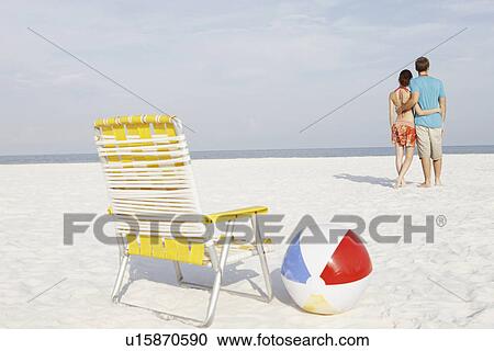 Young couple, chair and ball on beach View Large Photo Image Stock Image - Young couple, chair and ball on beach. Fotosearch