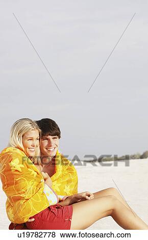 Young couple cuddling under towel on beach View Large Photo Image Stock Photo - Young couple cuddling under towel on beach. Fotosearch