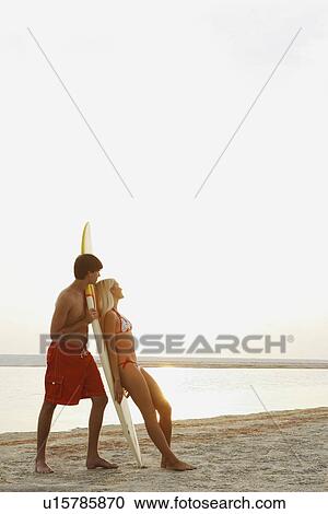 Stock Image - Young couple enjoying sunset on beach. Fotosearch