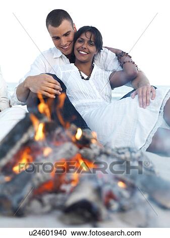 Young couple hugging by campfire on beach View Large Photo Image Stock Image - Young couple hugging by campfire on beach. Fotosearch
