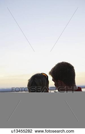 Stock Image - Young couple hugging on beach at sunset. Fotosearch