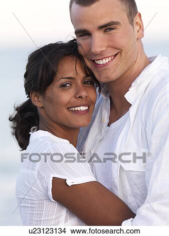 Picture - Young couple hugging on beach. Fotosearch