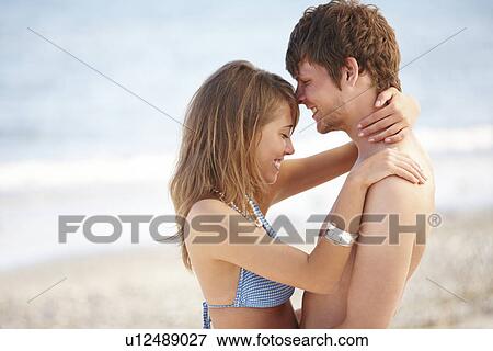 Stock Photo - Young couple hugging on beach. Fotosearch