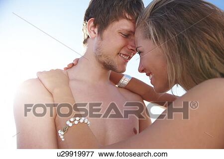Stock Photo - Young couple hugging on beach. Fotosearch