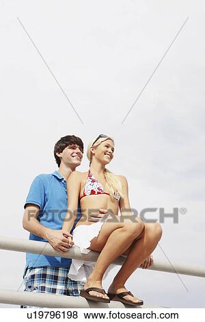 Young couple hugging on boardwalk railing View Large Photo Image Stock Photo - Young couple hugging on boardwalk railing. Fotosearch