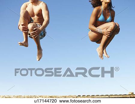 Young couple jumping of dock View Large Photo Image Stock Image - Young couple jumping of dock. Fotosearch