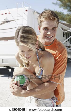 Stock Image - Young couple playing with football on beach. Fotosearch