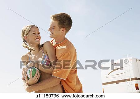 Stock Photograph - Young couple playing with football on beach. Fotosearch