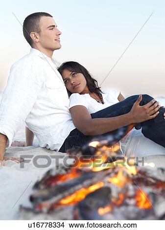 Young couple relaxing by campfire on beach View Large Photo Image Picture - Young couple relaxing by campfire on beach. Fotosearch