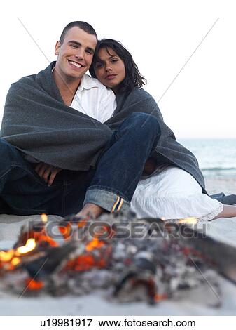 Young couple relaxing by campfire on beach View Large Photo Image Stock Photo - Young couple relaxing by campfire on beach. Fotosearch