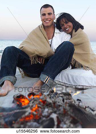 Young couple relaxing by campfire on beach View Large Photo Image Stock Photograph - Young couple relaxing by campfire on beach. Fotosearch