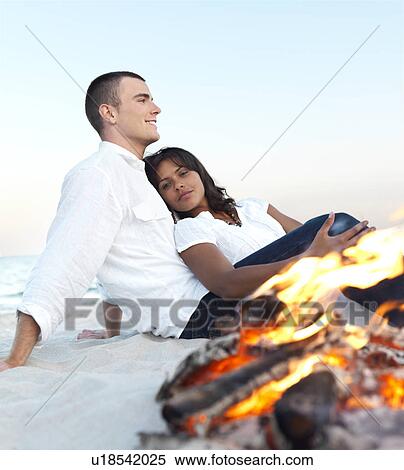 Young couple relaxing by campfire on beach View Large Photo Image Stock Photography - Young couple relaxing by campfire on beach. Fotosearch