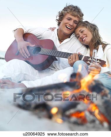 Young couple relaxing by campfire on beach View Large Photo Image Stock Photography - Young couple relaxing by campfire on beach. Fotosearch