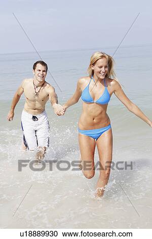Young couple running in ocean View Large Photo Image Stock Image - Young couple running in ocean. Fotosearch