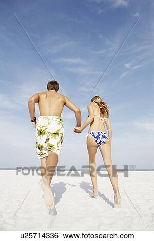 Young couple running on beach View Large Photo Image Stock Photograph - Young couple running on beach. Fotosearch
