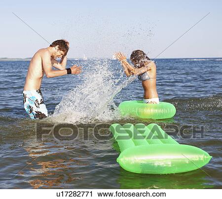 Young couple splashing in ocean View Large Photo Image Stock Image - Young couple splashing in ocean. Fotosearch